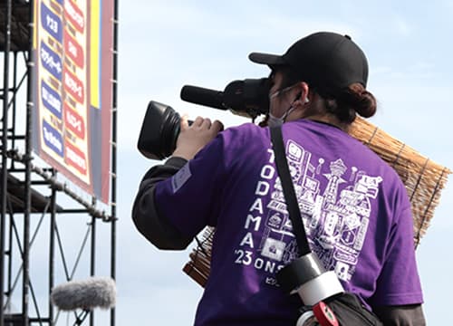 屋外のイベントでカメラの機材を操る男子生徒