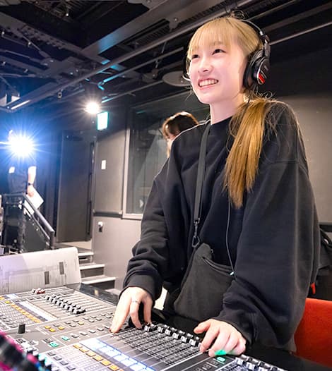 ヘッドホンをして音響機器を操作する女子学生